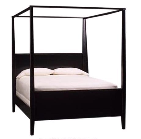 A chic and simple dark wood canopy bed frame, with neutral sheets and duvet