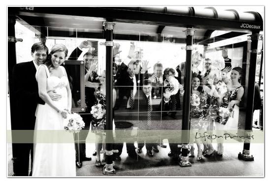 Bride, groom and wedding party have fun posing at bus stop in this black and white wedding photo