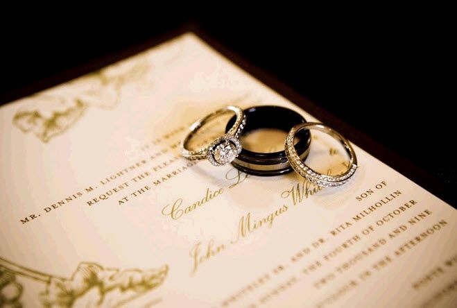 Ivory and olive green elegant wedding invitations with wedding rings sitting on top