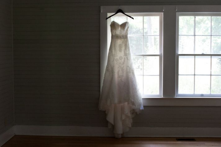 Classic and romantic ivory lace strapless wedding dress hangs in window