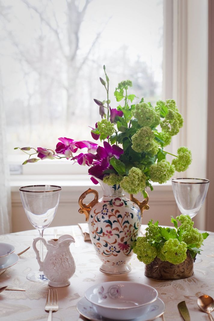 Purple orchids and green flowers arranged in antique wedding reception vase