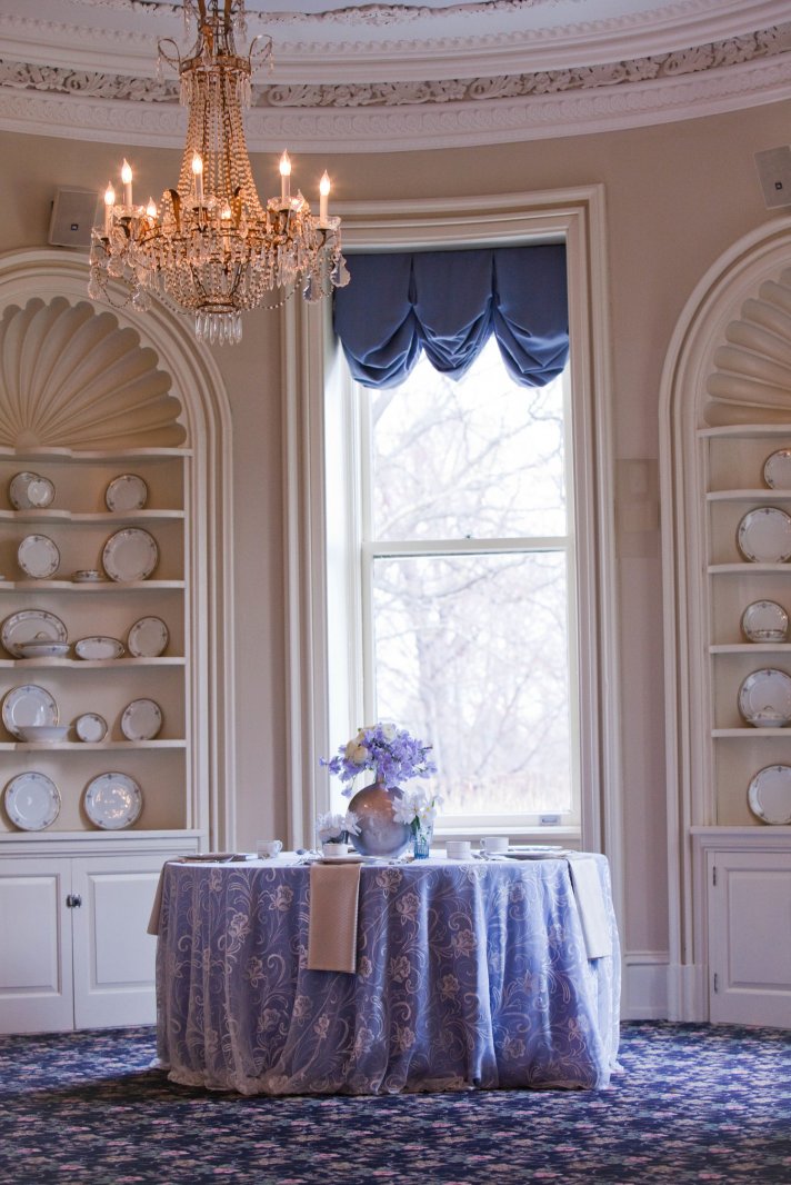 Elegant wedding reception venue with sparkling chandelier, blue, lilac ivory wedding flowers