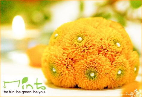 Bright, sunny, yellow-orange round floral arrangement, pearls in middle of each flower