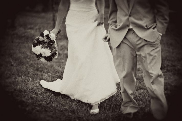 Wedding photo of bride in white wedding dress, groom in taupe morning suit, hand in hand