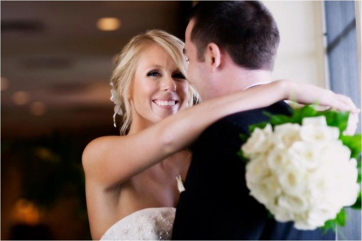 Beautiful bride holds ivory rose bridal bouquet and her handsome groom