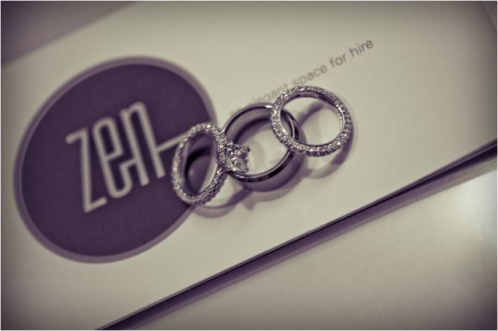 Diamond engagement ring and wedding bands photographed on wedding venue sign