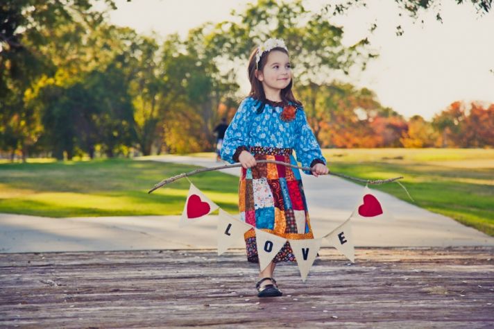 Adorable flower girl holds Love sign for outdoor California wedding