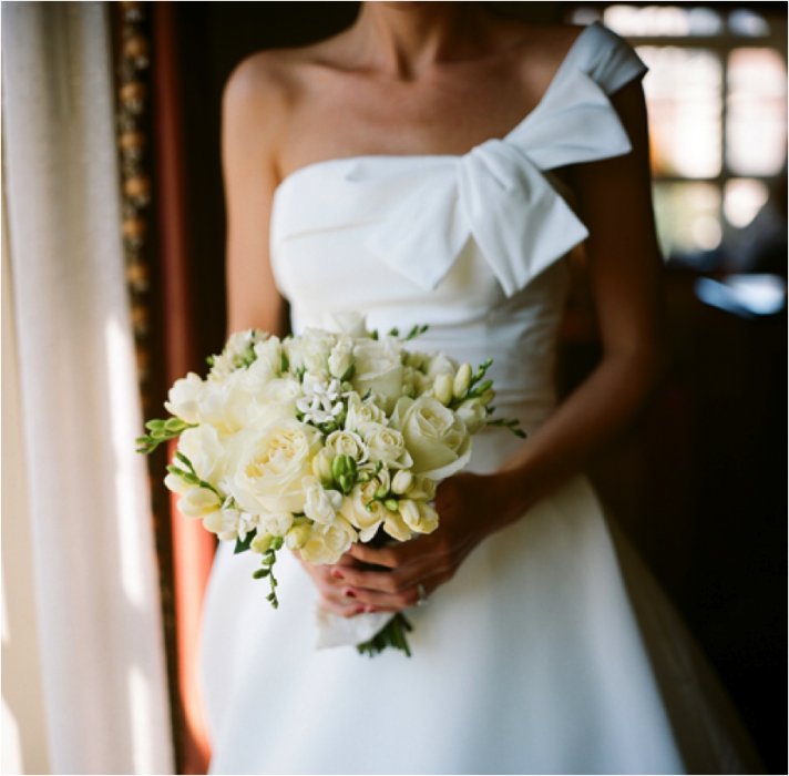 White one-shoulder wedding dress and ivory bridal bouquet