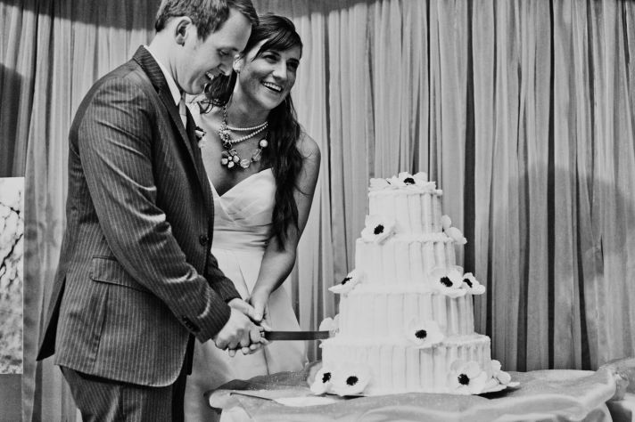 Bride and groom cut ivory wedding cake at wedding reception in Kansas City
