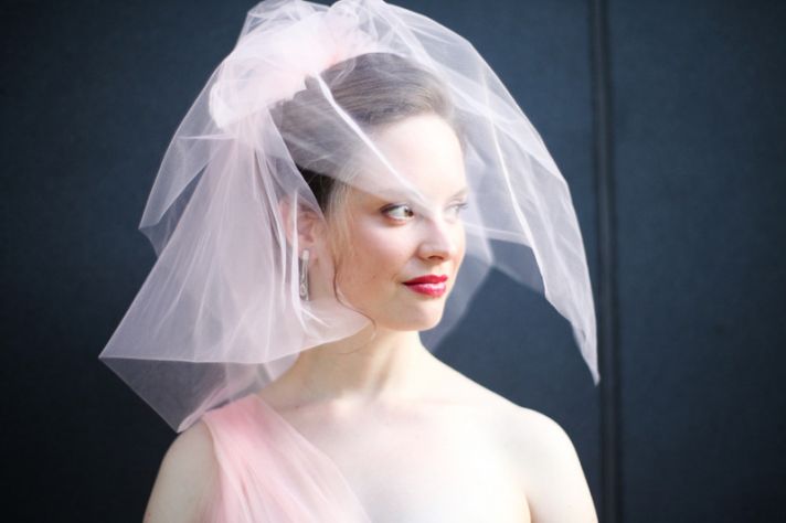 bride wears blush pink wedding dress birdcage veil