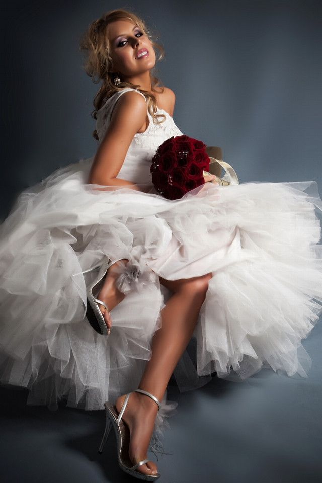 Assymentrical wedding dress (one shoulder) with full tulle skirt, bride holds dark red rose bridal b