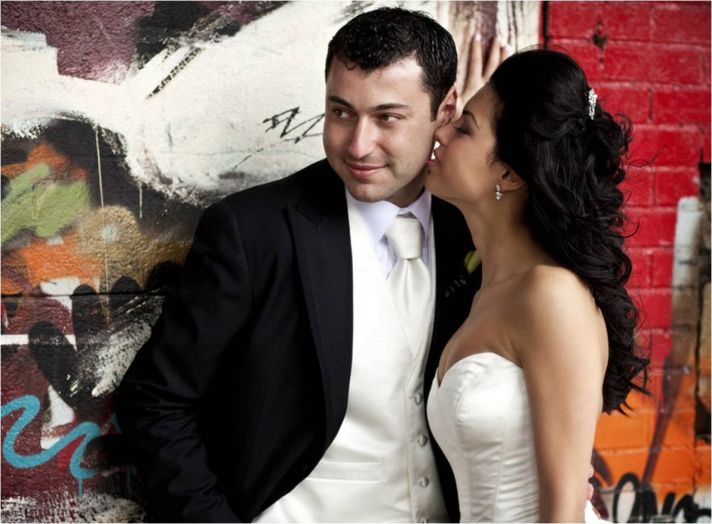 The bride in her ivory Vera Wang wedding dress with a sweetheart neckline whispers into her groom’s 