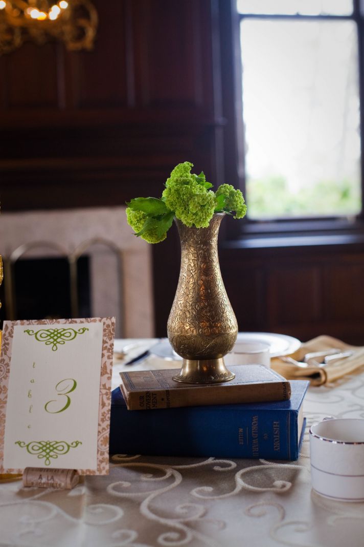 Green wedding flowers in antique copper vase for wedding reception table centerpiece