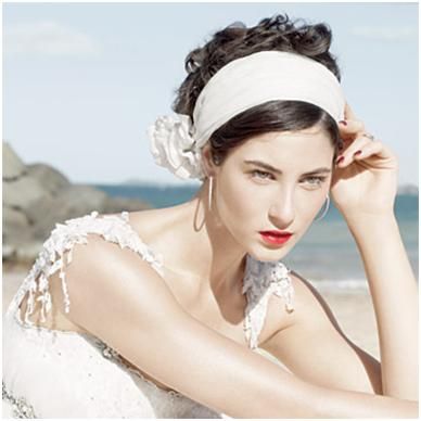 Bride wears white headband with satin flower on the side
