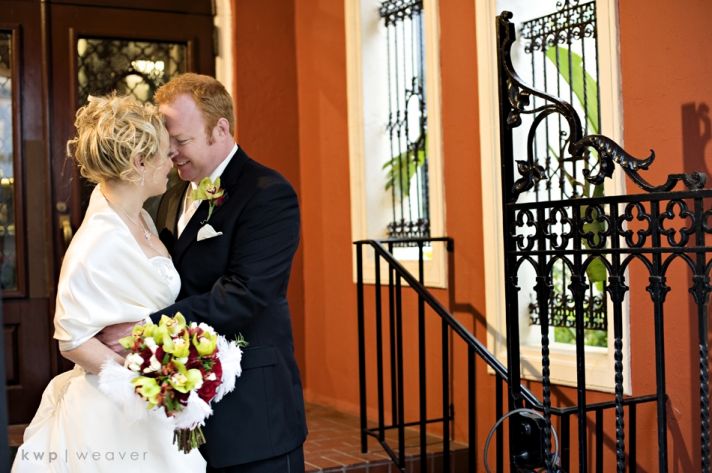 Beautiful bride in white wedding dress and white fur stole, holds dark red and green bridal bouquet,
