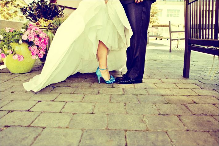 Bride in white sweetheart neckline wedding dress and blue bridal heels poses with groom