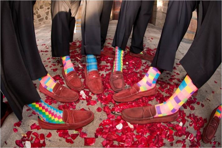 Groom and groomsmen show off red suede shoes and funky colorful socks