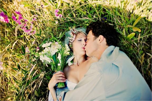 Eco-friendly bride and groom kiss in grass at outdoor wedding venue