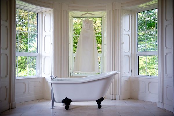 Ivory wedding dress hangs in window of wedding venue