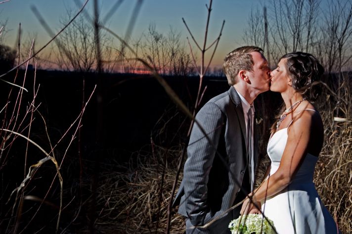 Bride and groom kiss outside during sunset, captured by Kansas City wedding photographer
