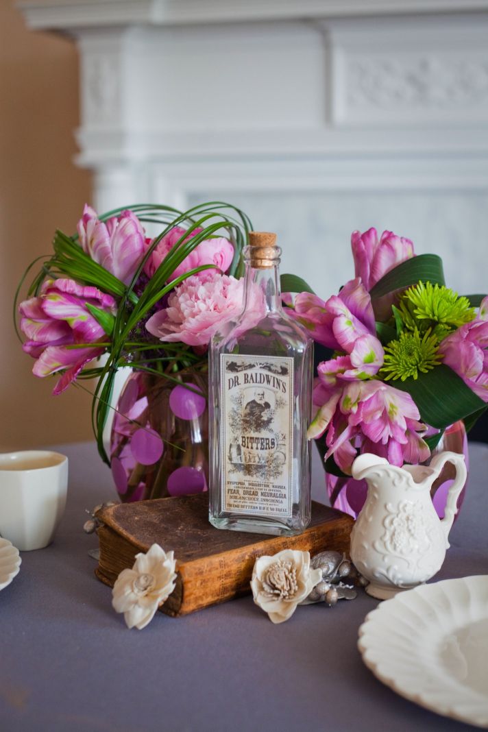 Wedding reception centerpieces of pink peonies with vintage bottles and other table details