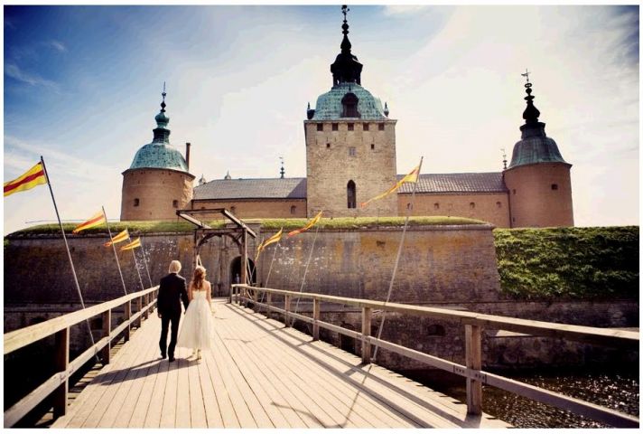 Bride and groom walk together hand in hand towards beautiful castle in Sweden