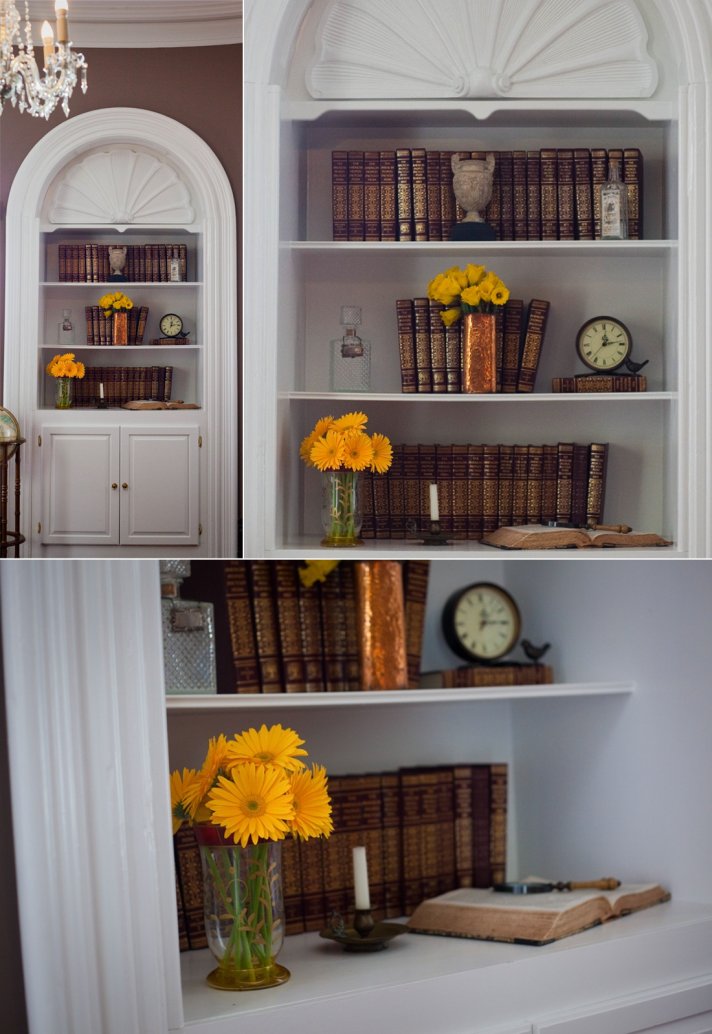 Vintage bookshelf adorned with yellow wedding flowers, metallic accents