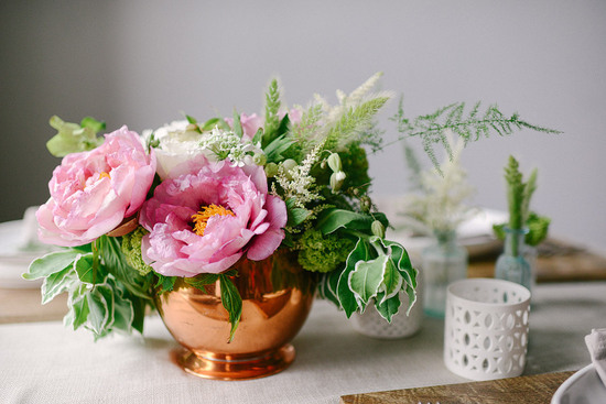 photo of Wedding centerpiece of pink peonies and leaves in copper vase