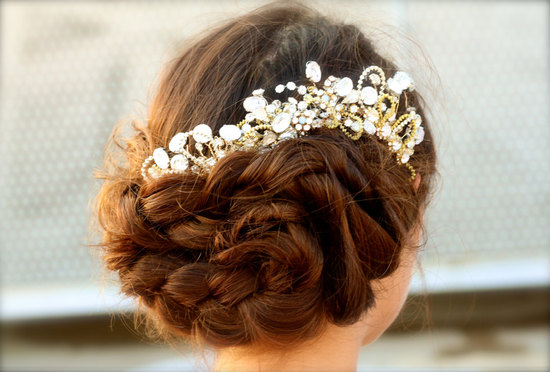 Low braided wedding updo finished with a gold and crystal headpiece