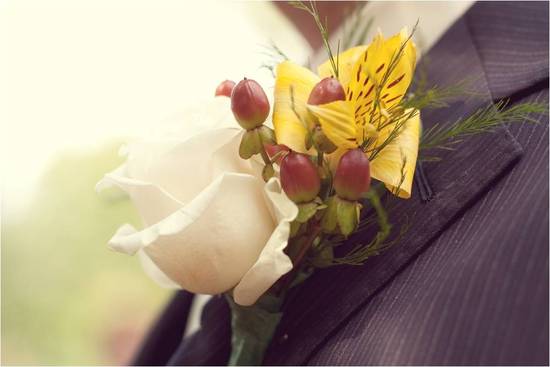 Groom wears pin stripe suit and ivory, yellow, berry red boutonnière