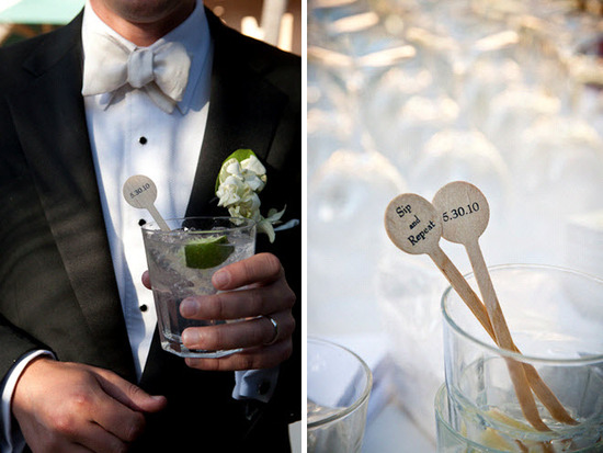 Groom wears black tux, ivory bowtie, white shirt, holds cocktail with personalized stir stick