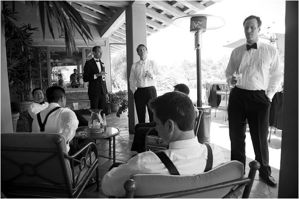 Groom-groomsmen-in-classic-black-tuxedos-black-bowties-mingle-with-cocktails-before-wedding.full