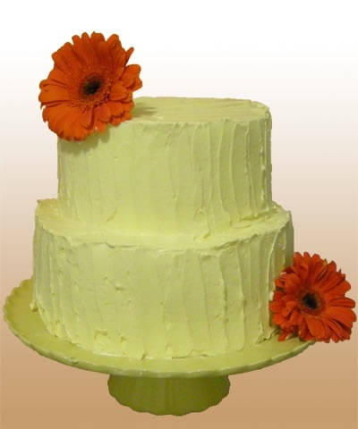 This green two tiered cake is simply decorated with orange daisies.