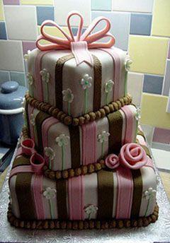 photo of Whimsical wedding cake with pink and brown stripes, delicate white and green flowers and a pink ribb