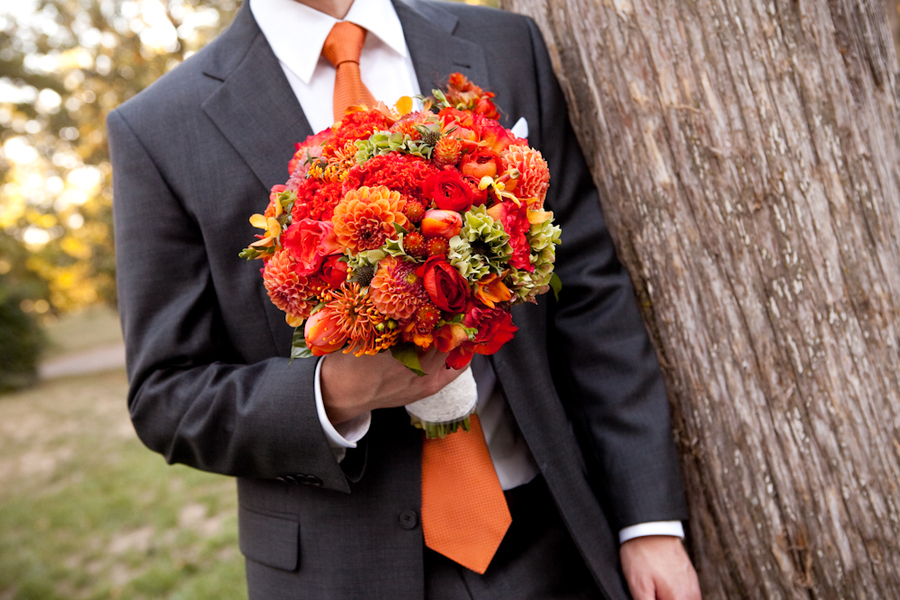 Vibrant-orange-bridal-bouquet-held-by-groom.full