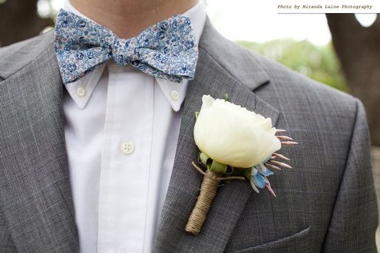 photo of mens wedding attire groom wears blue bow tie floral print grey tailored suit